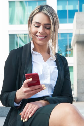 cheerful-businesswoman-texting-phone-outdoors